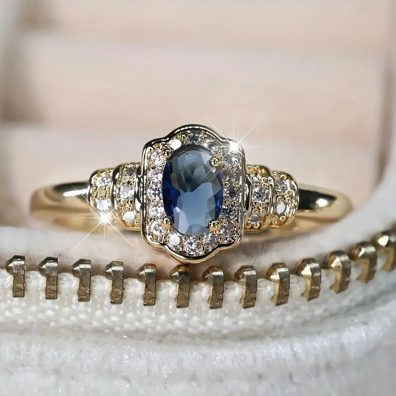 18K gold-plated promise ring featuring a vibrant blue gemstone in the center, framed by dazzling cubic zirconia. 