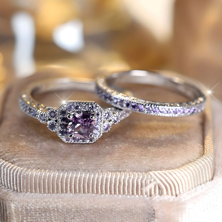 Two elegant promise rings for women: one has a bold purple gemstone, and the other sparkles with small accent stones. Set on a soft beige surface, these rings are simply beautiful.