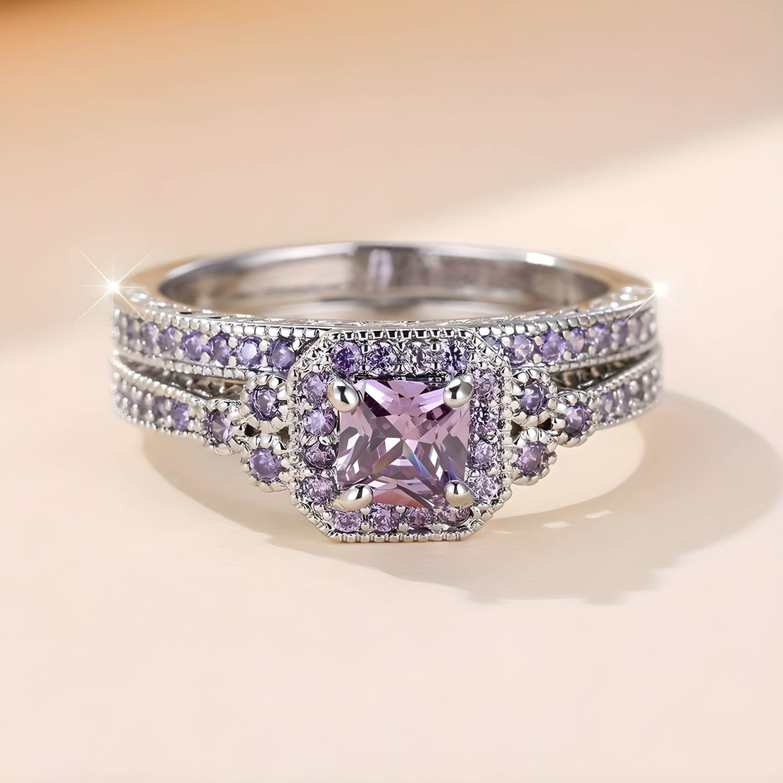 Front view of a promise ring for women, which features a pink square-cut gemstone surrounded by small purple crystals, with matching stones along the band.