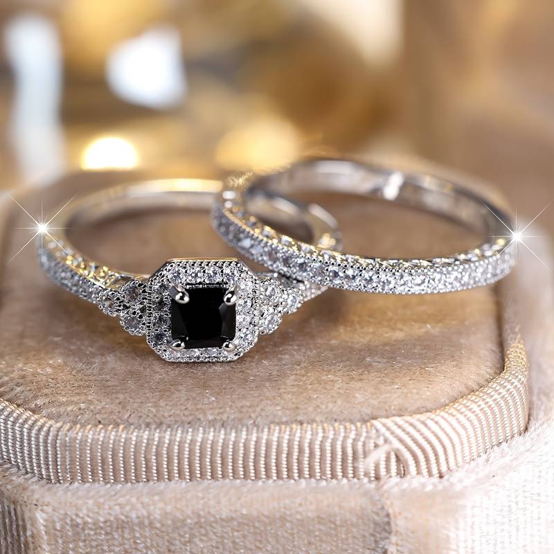 Elegant promise rings for women with a black gemstone centerpiece and sparkling diamond accents on a silver band.