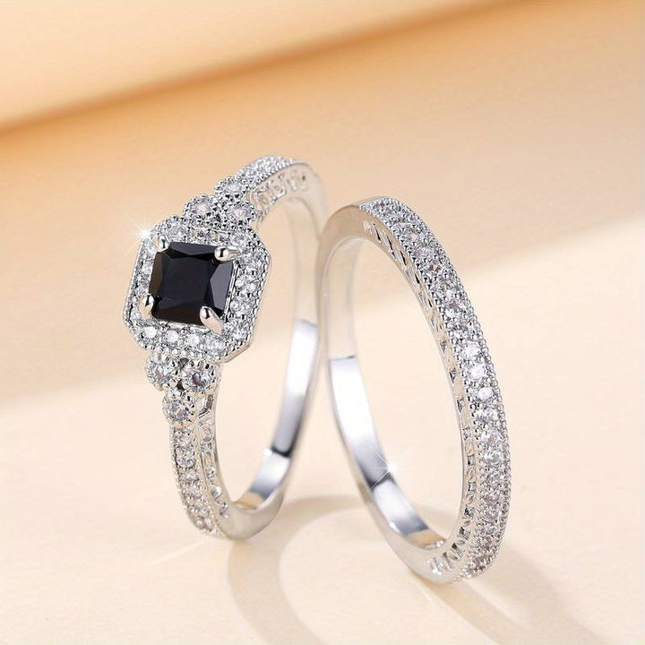  A pair of promise rings for women, one with a square black gemstone surrounded by small diamonds and another with a sleek, matching diamond-studded band, both crafted in silver, showcasing a timeless and elegant design.