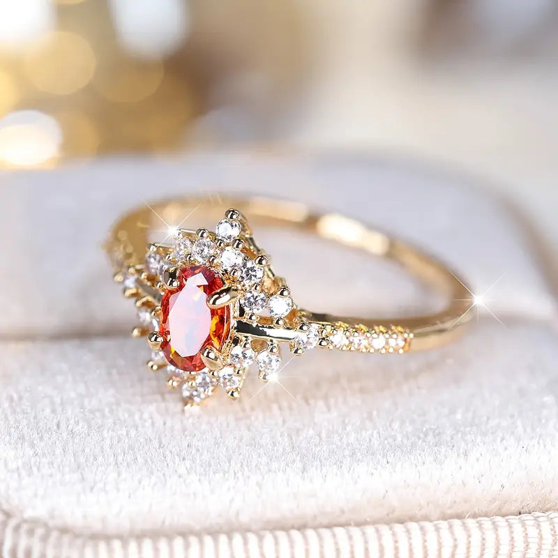 Close-up of a gold-plated ring showcasing an orange gemstone encircled by dazzling cubic zirconia stones.