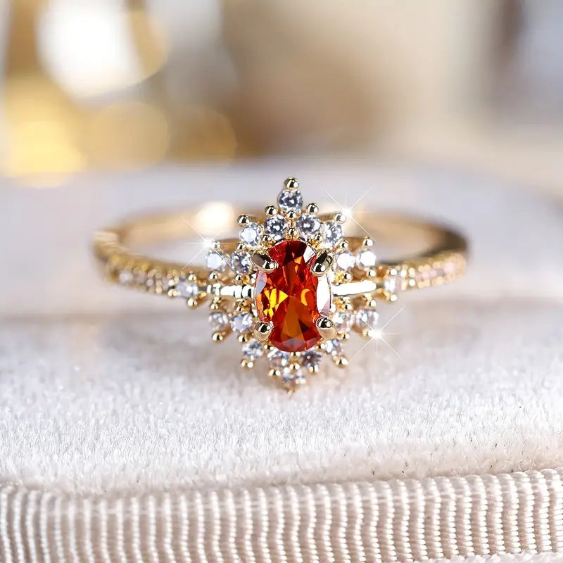 Stunning gold-plated ring with a radiant orange gemstone centerpiece, highlighted by a halo of cubic zirconia.