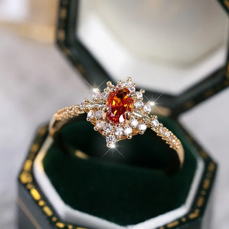 Gold-plated ring with a vibrant orange gemstone and sparkling cubic zirconia on a luxurious background.