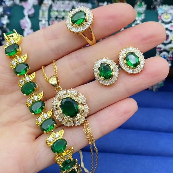 Close-up of a hand showcasing a stunning 18K gold plated jewellery set adorned with vibrant green gemstones, highlighting the elegance and intricate design of the jewelry.