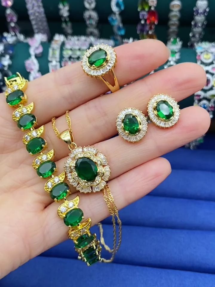 Close-up of a hand showcasing a stunning 18K gold plated jewellery set adorned with vibrant green gemstones, highlighting the elegance and intricate design of the jewelry.